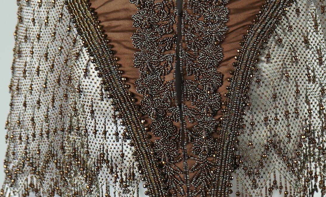 A late 19th century ladies ornate steel and brown beaded and fringed shoulder cape. Made as three ribbed silk panels with ornate beaded appliqués with a beaded and fringed net sleeved cape. Top of neck to bottom of beadi